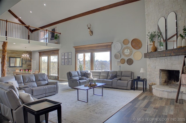 living area featuring baseboards, ornamental molding, a fireplace, a towering ceiling, and wood finished floors