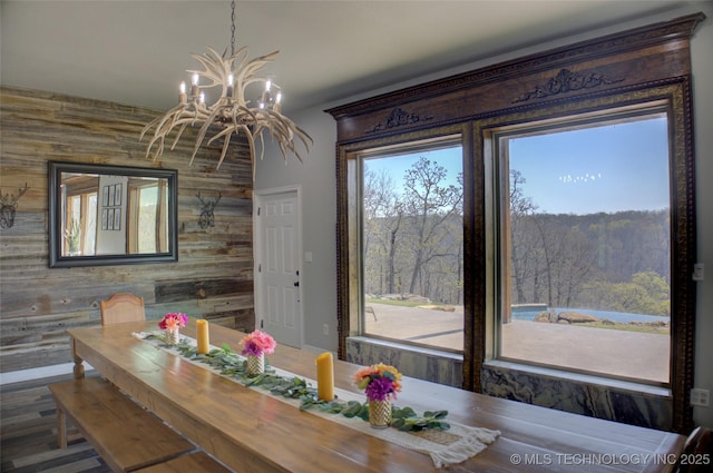 dining space featuring wood walls and a chandelier