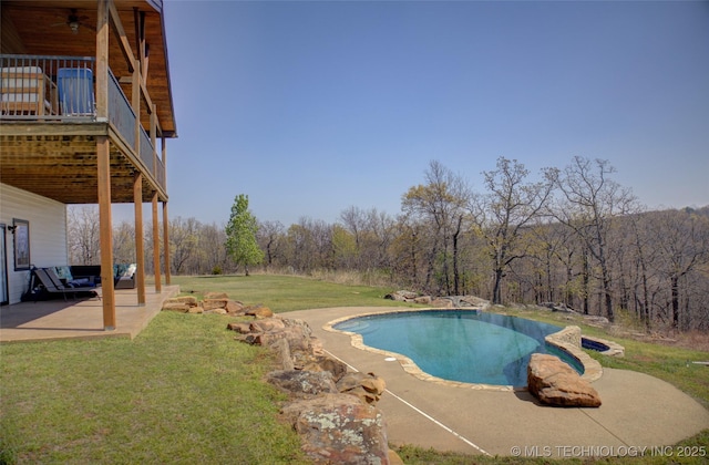 outdoor pool featuring a lawn, a ceiling fan, a view of trees, and a patio area