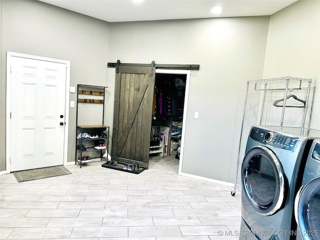 laundry room with laundry area, independent washer and dryer, a barn door, baseboards, and light wood-type flooring