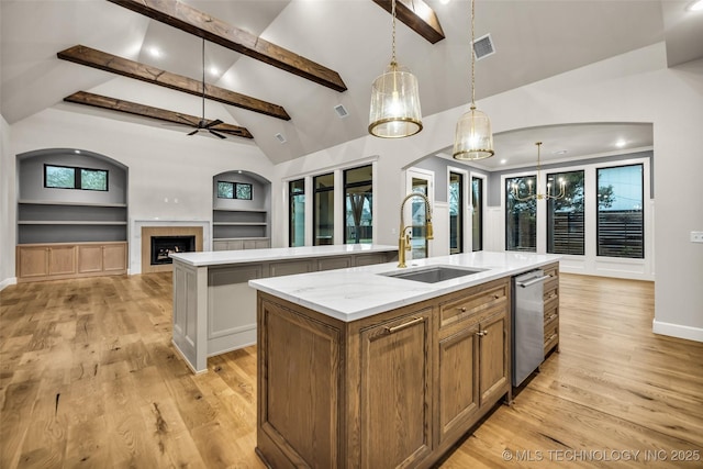 kitchen featuring visible vents, built in features, a sink, and a center island with sink