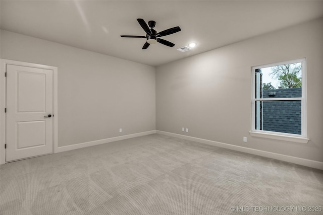 empty room featuring ceiling fan, light carpet, visible vents, and baseboards