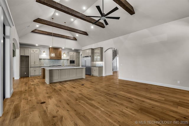 kitchen featuring arched walkways, stainless steel built in refrigerator, beamed ceiling, and ceiling fan