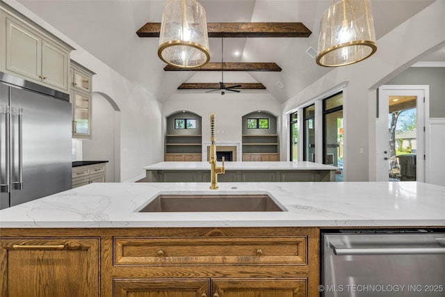kitchen featuring stainless steel appliances, light stone counters, a sink, beam ceiling, and ceiling fan