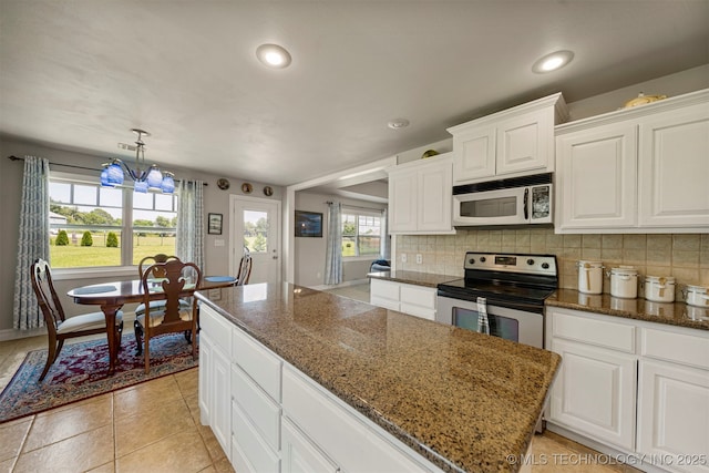 2003 Estates, Grove, OK 74344 - kitchen with tasteful backsplash, dark stone countertops, stainless steel range with electric stovetop, white microwave, and white cabinetry