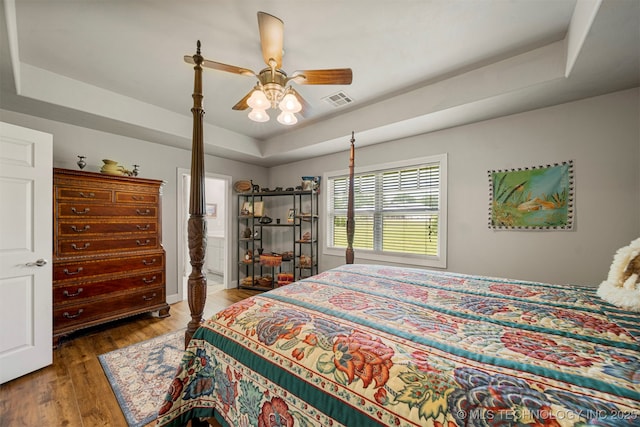 2003 Estates, Grove, OK 74344 - bedroom with ensuite bathroom, visible vents, a tray ceiling, ceiling fan, and wood finished floors
