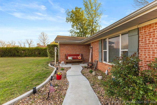doorway to property featuring a lawn and brick siding