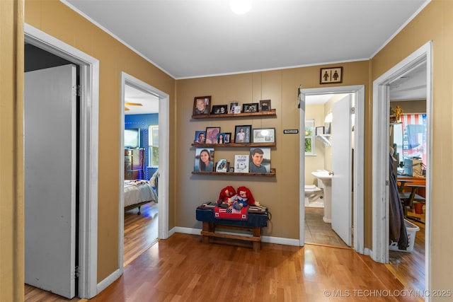 hallway with wood finished floors, baseboards, and ornamental molding