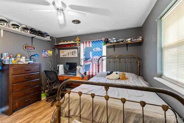 bedroom with a ceiling fan, wood finished floors, and multiple windows