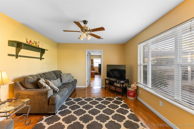 living room featuring baseboards, a ceiling fan, and wood finished floors
