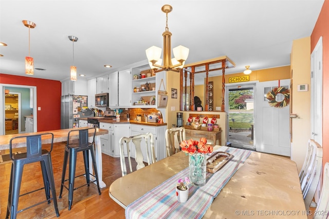 dining space with recessed lighting, an inviting chandelier, and wood finished floors