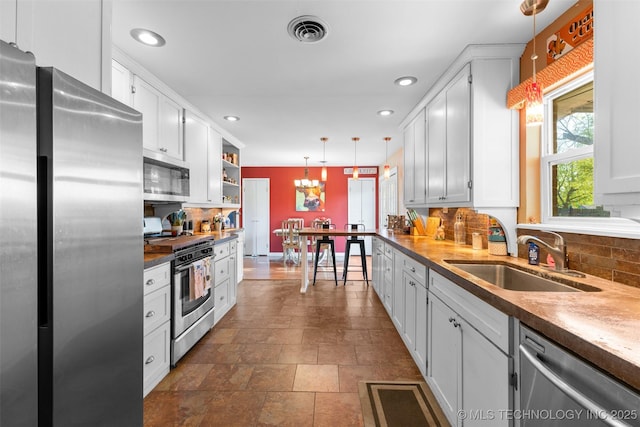 kitchen featuring appliances with stainless steel finishes, a sink, backsplash, and visible vents