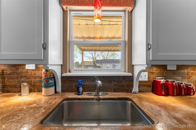 details featuring tasteful backsplash, a sink, and light stone counters