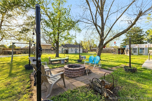 view of yard featuring fence, an outdoor structure, a fire pit, and a patio