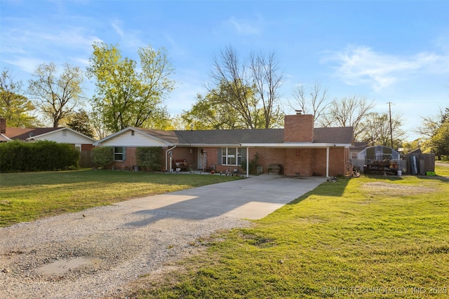 ranch-style house featuring a front yard, a carport, a chimney, concrete driveway, and brick siding