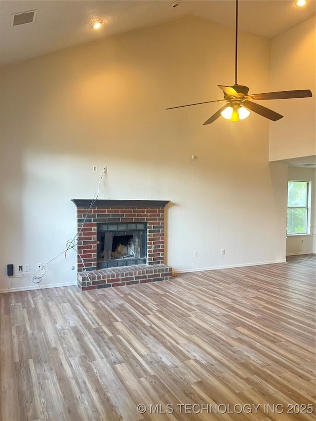 unfurnished living room featuring wood finished floors, a ceiling fan, baseboards, a brick fireplace, and high vaulted ceiling