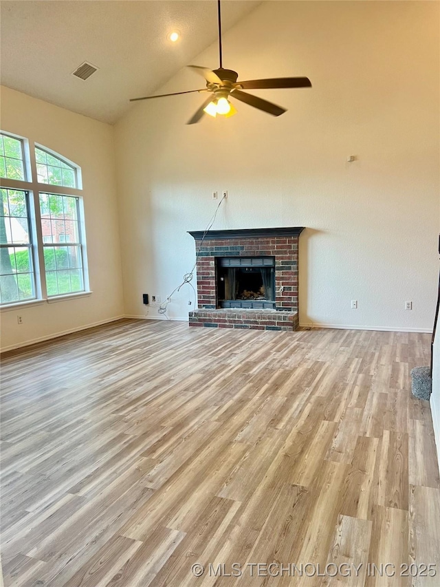 unfurnished living room with light wood finished floors, baseboards, visible vents, lofted ceiling, and a ceiling fan