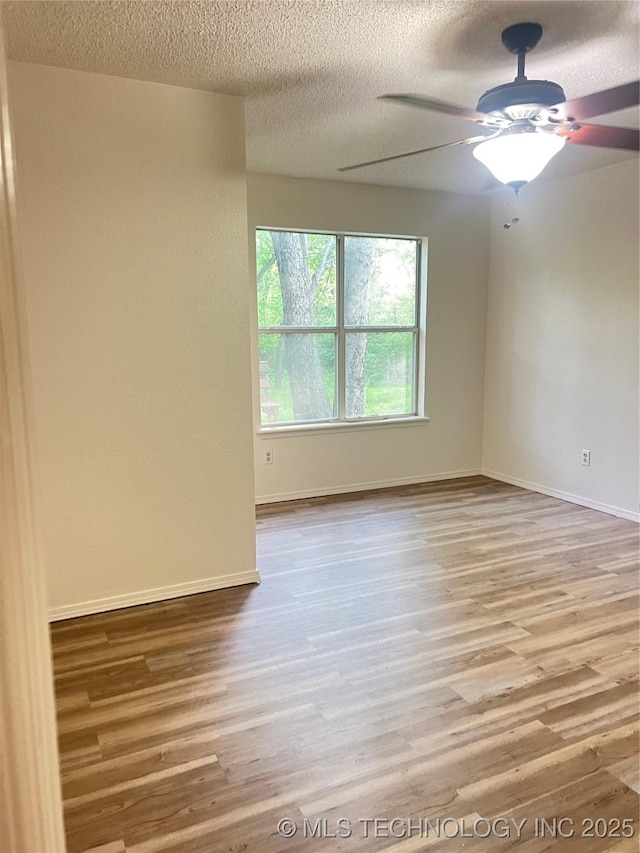 unfurnished room featuring baseboards, wood finished floors, a textured ceiling, and ceiling fan