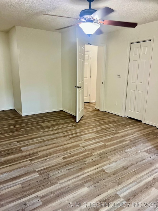 unfurnished bedroom featuring wood finished floors, a textured ceiling, and ceiling fan