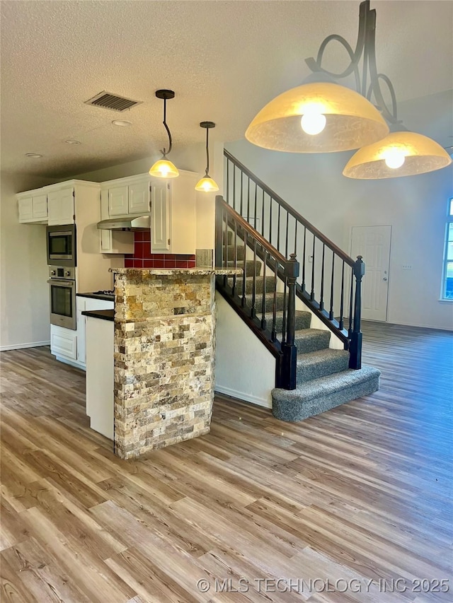 kitchen with dark countertops, wood finished floors, visible vents, and appliances with stainless steel finishes