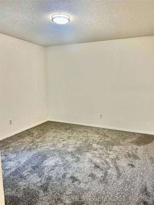 spare room with baseboards, carpet flooring, and a textured ceiling