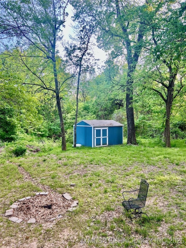 view of yard with an outbuilding, a storage unit, and a wooded view