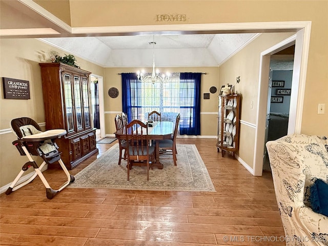 dining area featuring baseboards, vaulted ceiling, ornamental molding, a chandelier, and wood finished floors