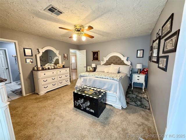 carpeted bedroom with a textured ceiling, baseboards, a ceiling fan, and visible vents