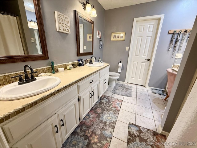bathroom with toilet, tile patterned floors, double vanity, and a sink