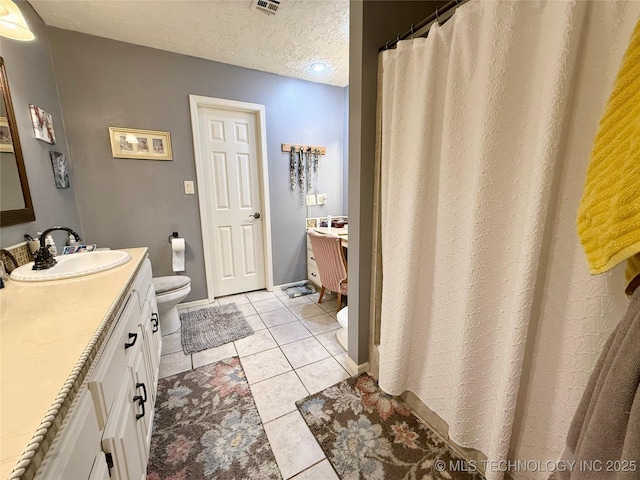 full bath with tile patterned flooring, vanity, a textured ceiling, and toilet