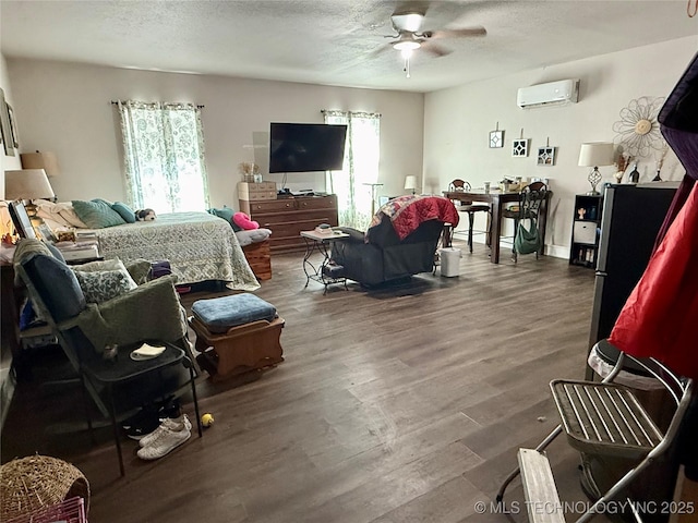 bedroom featuring a textured ceiling, a wall unit AC, wood finished floors, and multiple windows