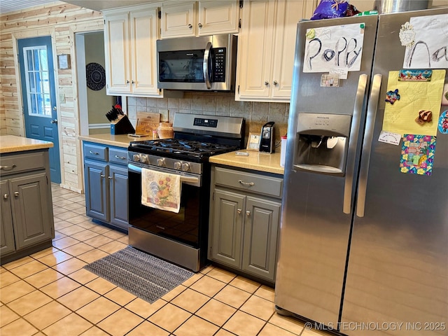 kitchen featuring gray cabinetry, tasteful backsplash, light countertops, and appliances with stainless steel finishes