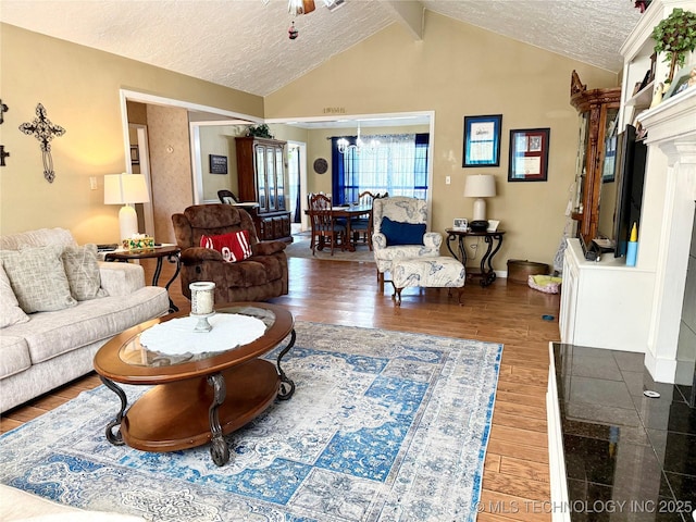 living area featuring baseboards, a textured ceiling, wood finished floors, and lofted ceiling with beams