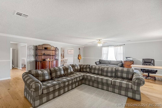 living area with visible vents, ceiling fan, light wood-style floors, a textured ceiling, and crown molding