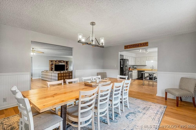 dining room featuring a textured ceiling, wainscoting, and light wood-style floors