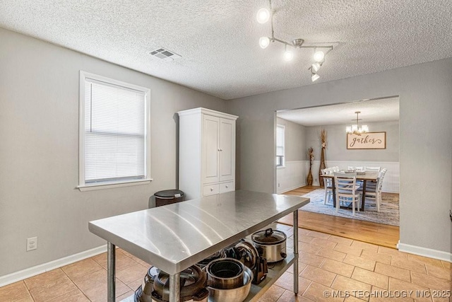 kitchen featuring visible vents, white cabinets, light tile patterned floors, an inviting chandelier, and a textured ceiling