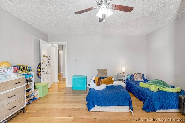 bedroom with light wood-style flooring, a ceiling fan, and a textured ceiling