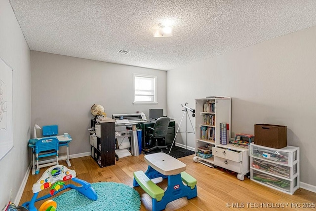 office space with a textured ceiling, wood finished floors, baseboards, and visible vents
