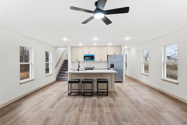 2002 W Driftwood Dr, Claremore, OK 74017 - kitchen featuring a kitchen island with sink, tasteful backsplash, stainless steel fridge with ice dispenser, and light wood-style floors