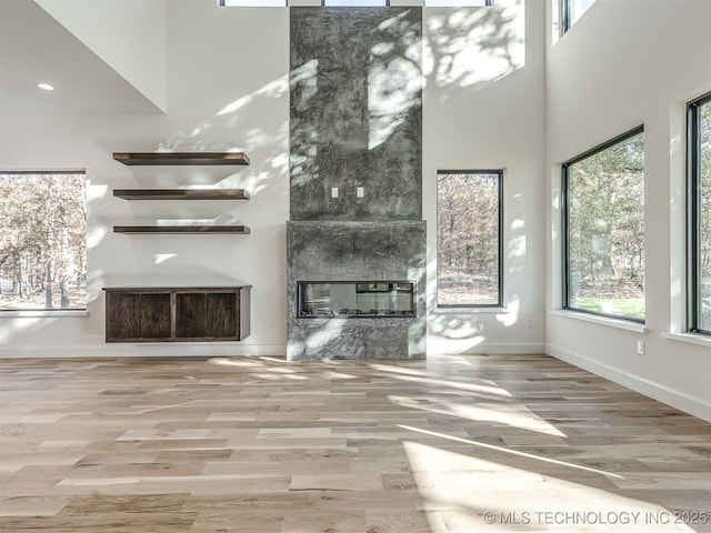 12415 Lakeview Rd, Sperry, OK 74073 - unfurnished living room featuring wood finished floors, a high end fireplace, a towering ceiling, and baseboards