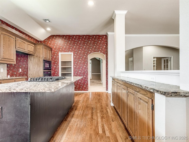 kitchen with wallpapered walls, light stone counters, black microwave, light wood-style flooring, and visible vents