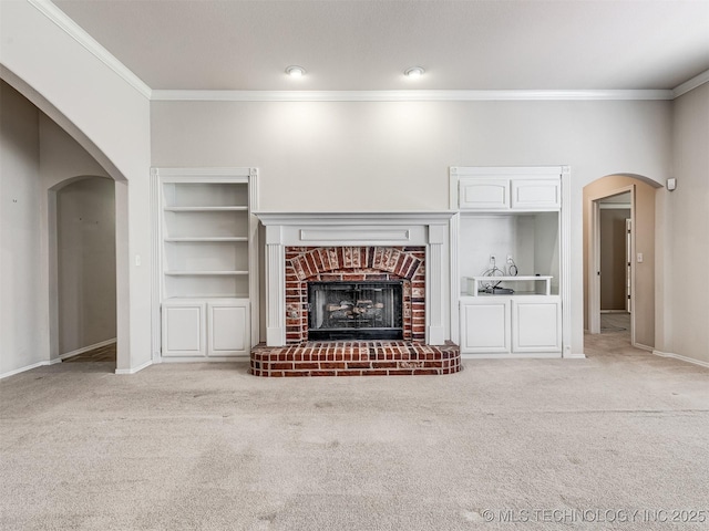 unfurnished living room featuring ornamental molding, carpet flooring, arched walkways, and a fireplace