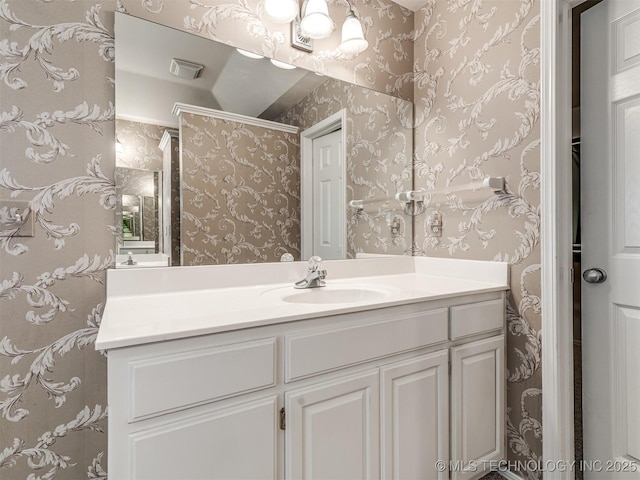 bathroom with wallpapered walls, vanity, and visible vents