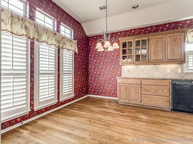 unfurnished dining area featuring light wood-style flooring, wallpapered walls, baseboards, and visible vents