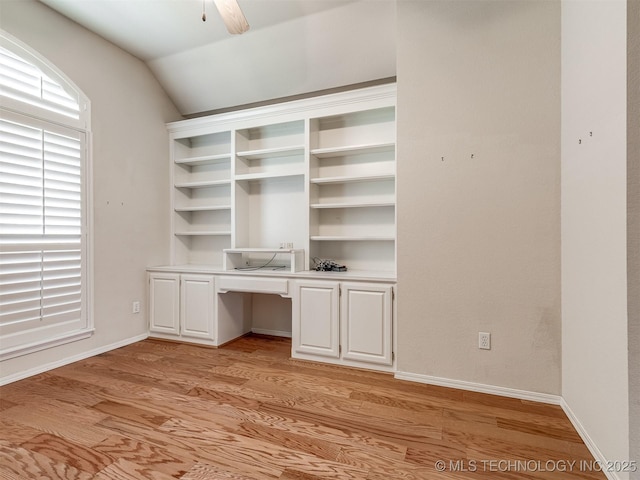 unfurnished office featuring lofted ceiling, baseboards, built in study area, ceiling fan, and light wood finished floors