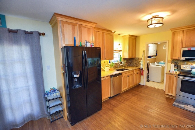 kitchen with light stone counters, tasteful backsplash, a sink, stainless steel appliances, and washer / clothes dryer