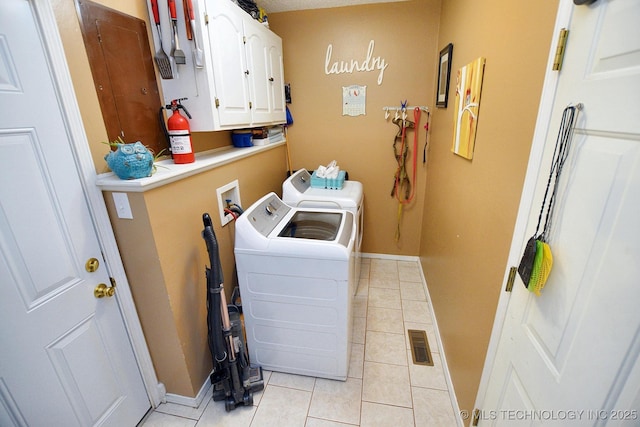 laundry room with washing machine and clothes dryer, baseboards, light tile patterned flooring, and cabinet space