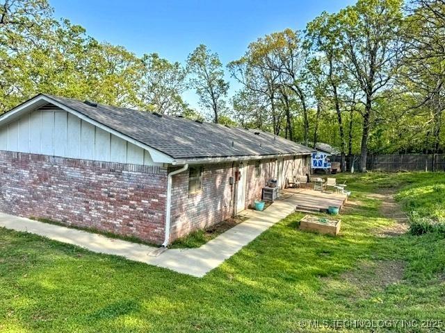 view of side of property with brick siding, a yard, and fence