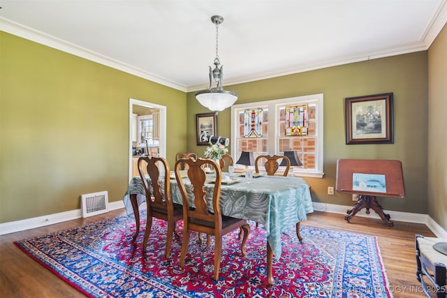 dining area featuring crown molding, wood finished floors, baseboards, and visible vents