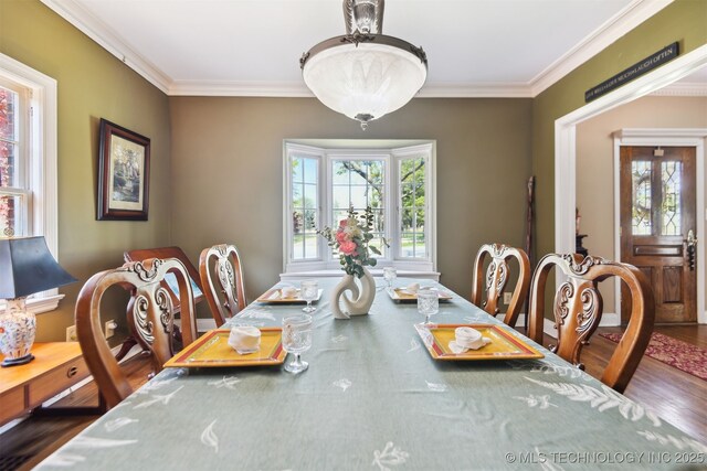 dining space with a wealth of natural light, crown molding, and wood finished floors